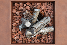 Load image into Gallery viewer, Decorative faux firewood logs and a pinecone arranged in a square terracotta-colored container filled with reddish-brown decorative stones.

