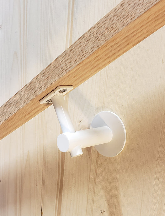 Modern handrail bracket, white color. attached to a custom wooden railing.